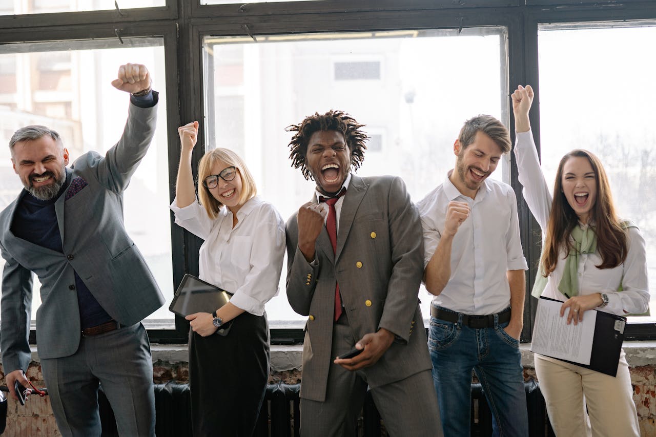 mission-img A joyful, diverse group of colleagues celebrating success indoors with cheerful expressions.
