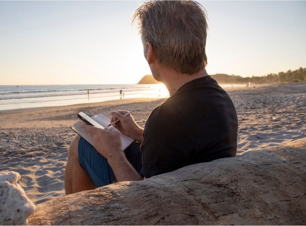 man journaling at the beach